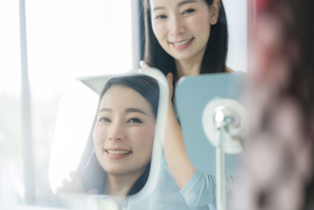 Woman admiring her new smile and teeth, reflecting the impact of smile design in dentistry