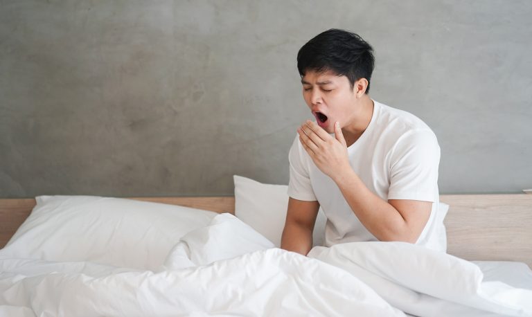 A man waking up with bad breath as a result of his snoring habits.