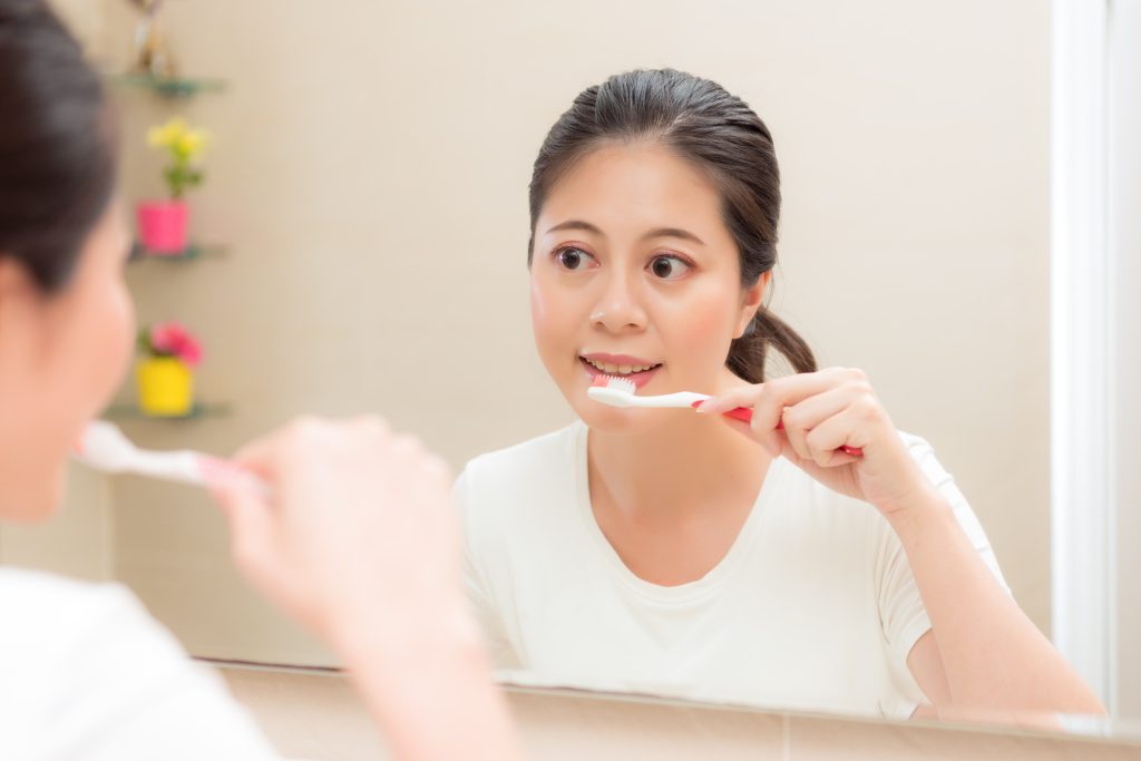 A woman maintaining good oral hygiene to cope with her bad breath.